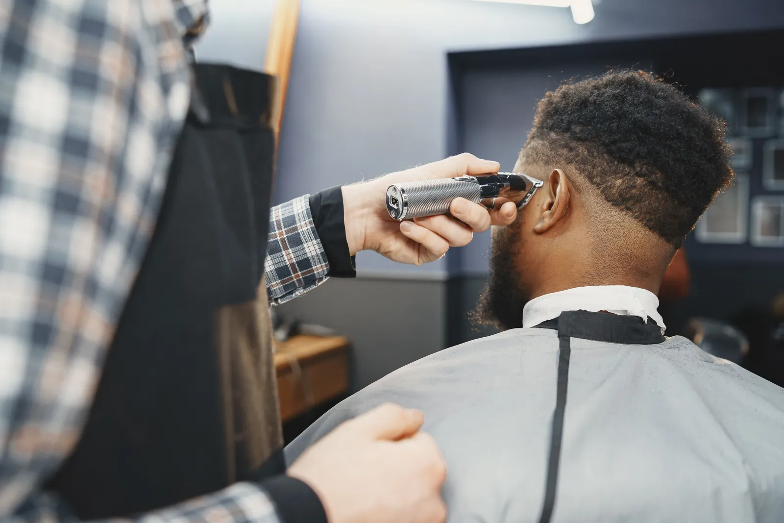 Barbeiro a fazer um fade à máquina na nuca de um cliente