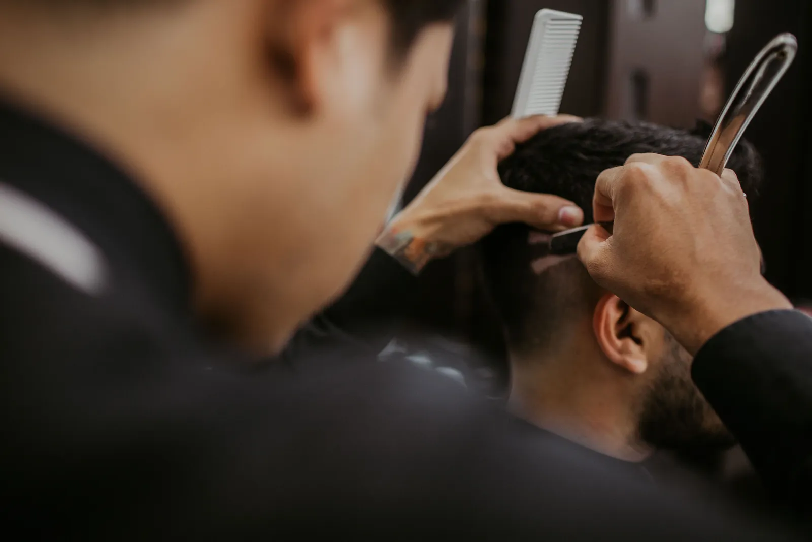 Mãos de barbeiro a acertar o cabelo com tesoura e pente